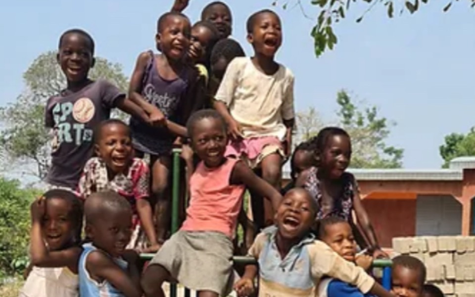 Grupa uśmiechniętych dzieci bawiących się na placu zabaw.