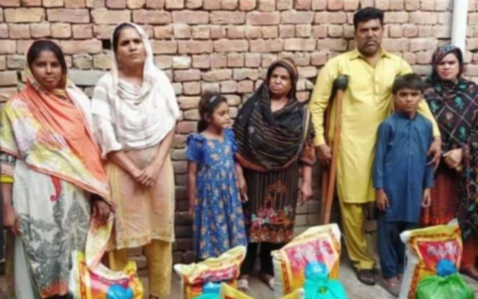 
        Rodzina pozująca przed ścianą z cegieł, z torbami z jedzeniem.
    