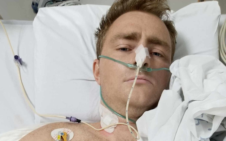 
        Mężczyzna leżący w szpitalu, z rurkami i monitorami.
    