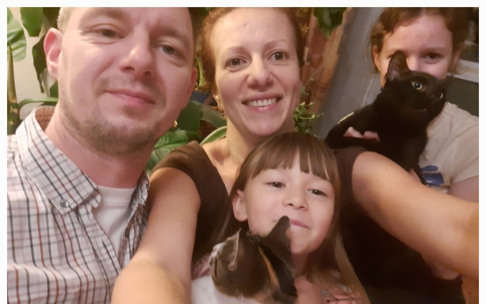 
        Rodzina pozująca do zdjęcia z kotami i zwierzętami domowymi.
    
