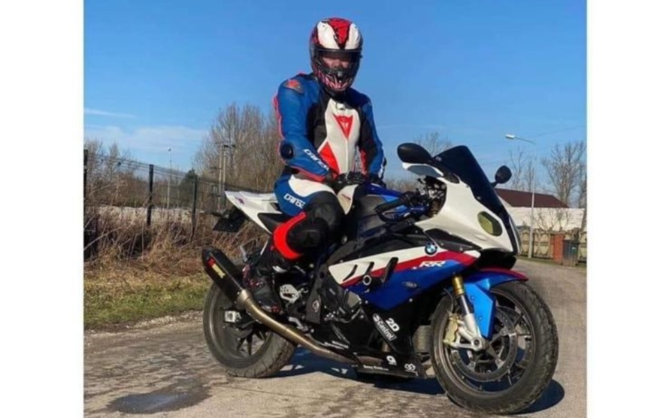 
        Motocyklista w kasku stoi obok sportowego motocykla.
    