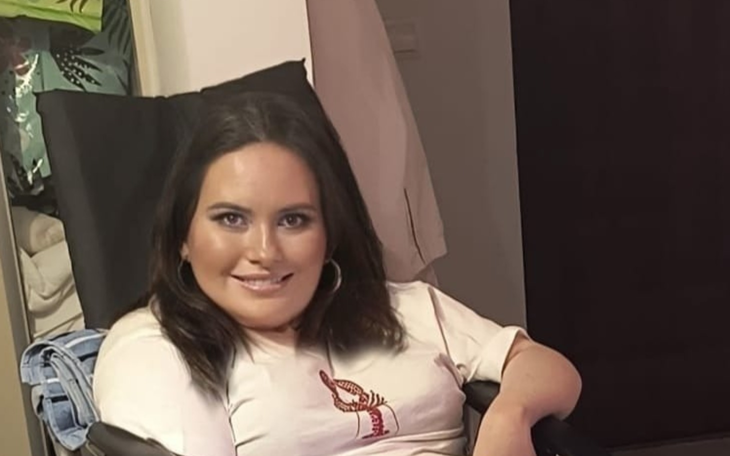 Kobieta siedząca na wózku, uśmiechająca się do kamery.