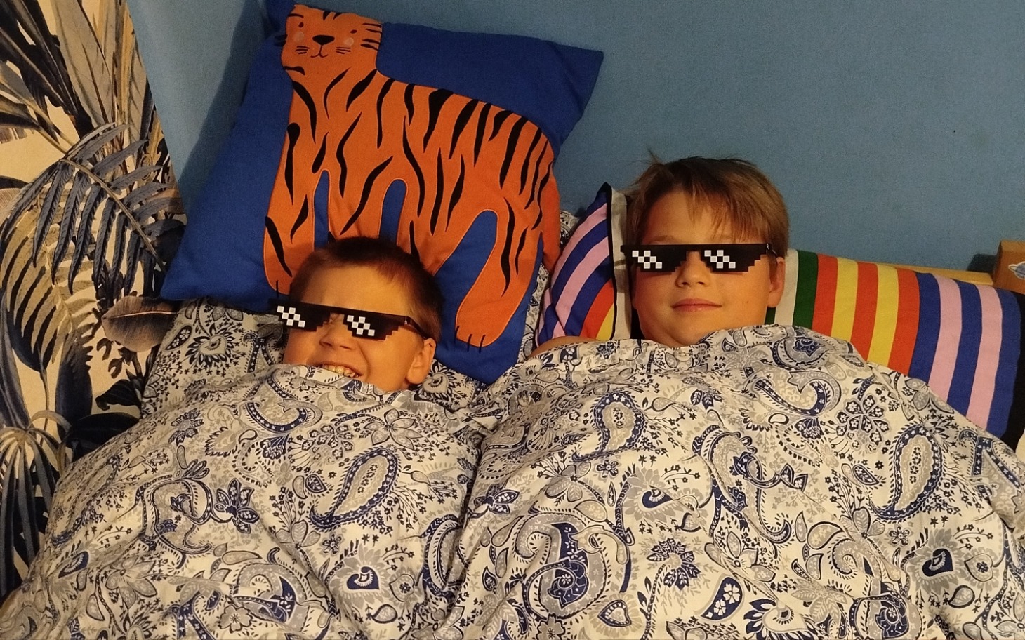 
        Dwóch chłopców w okularach przeciwsłonecznych, przykrytych kocem.
    