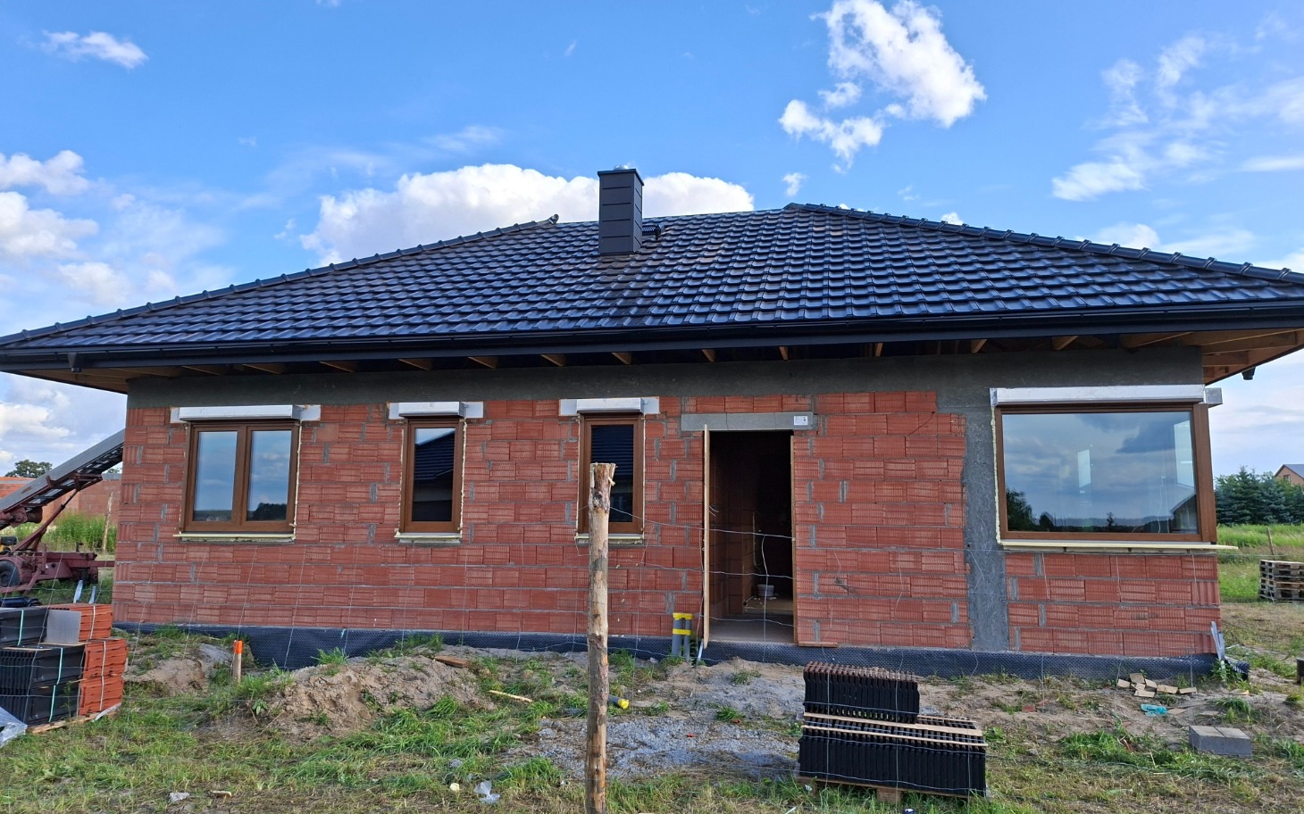 
        Nowo wybudowany dom z czerwonej cegły i oknami.
    