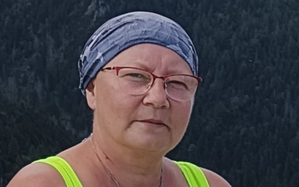 
        Kobieta w chustce na tle górskiego krajobrazu.
    
