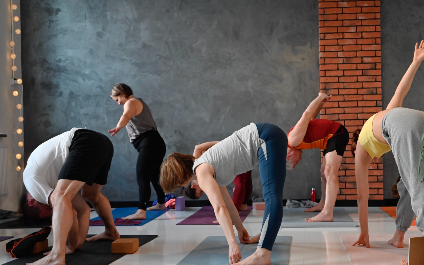 
        Grupa ludzi ćwiczących jogę w studiu.
    