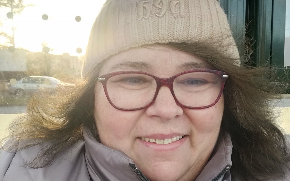 
        Uśmiechnięta kobieta w czapce, pozująca do zdjęcia.
    