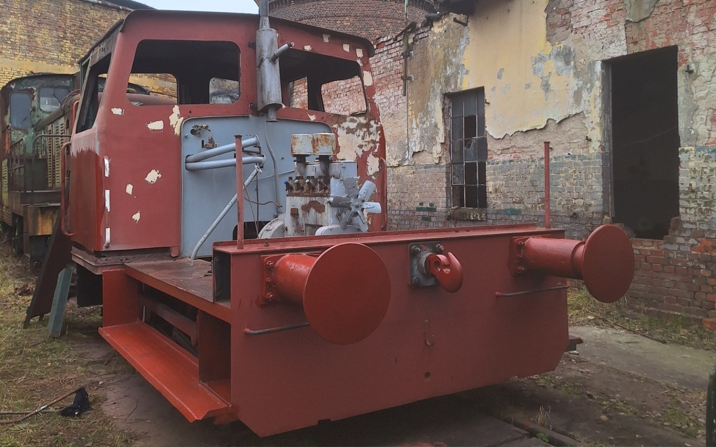 
        Stara lokomotywa w opuszczonym miejscu, zniszczona i zardzewiała.
    