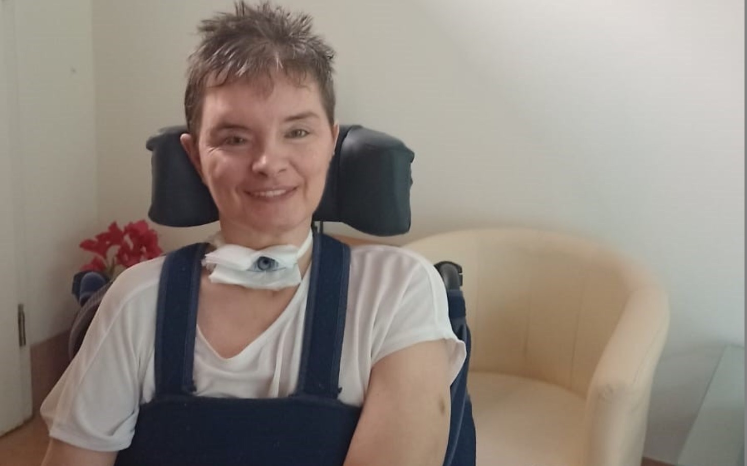 
        Kobieta na wózku inwalidzkim, uśmiechająca się do kamery.
    