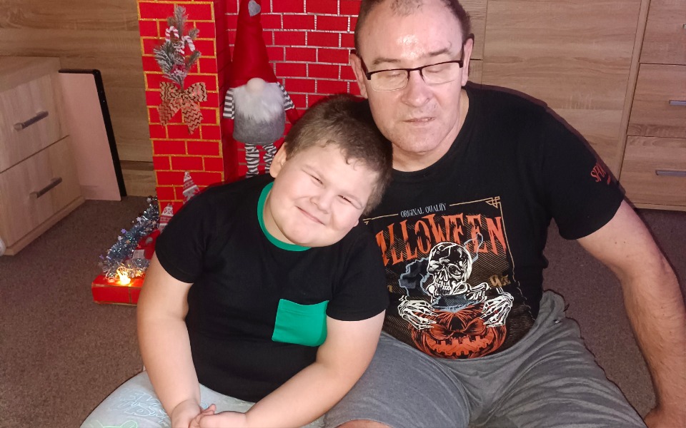 
        Chłopiec z dziadkiem, obaj uśmiechają się do zdjęcia.
    