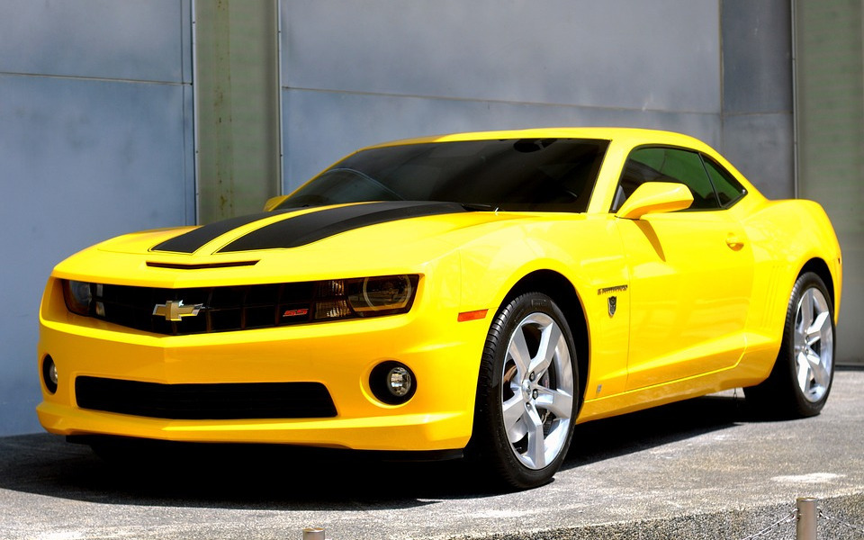 
        Żółty samochód sportowy Chevrolet Camaro na tle budynku.
    