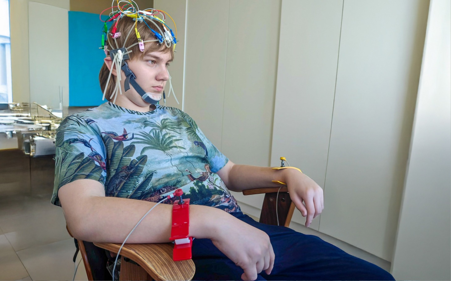 
        Młody mężczyzna z elektrodami na głowie, w skupieniu.
    