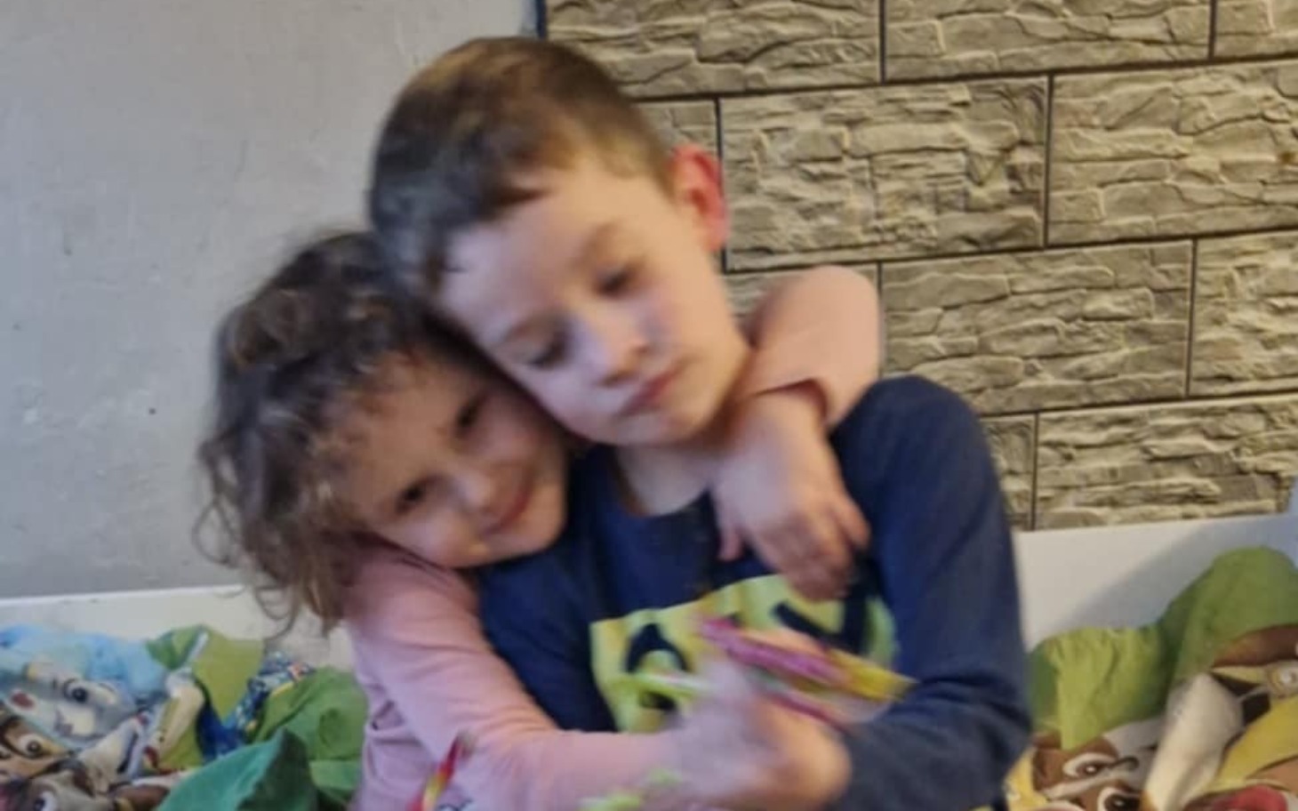 
        Dwoje dzieci przytulających się na kanapie.
    