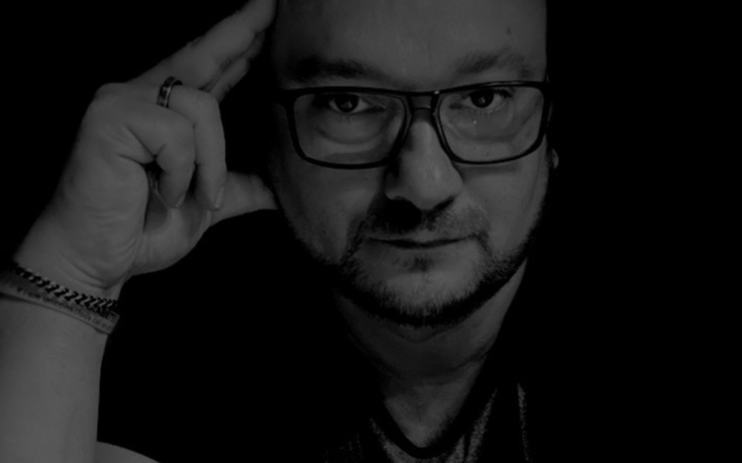 
        Mężczyzna w ciemnym otoczeniu, myślący z ręką przy głowie.
    