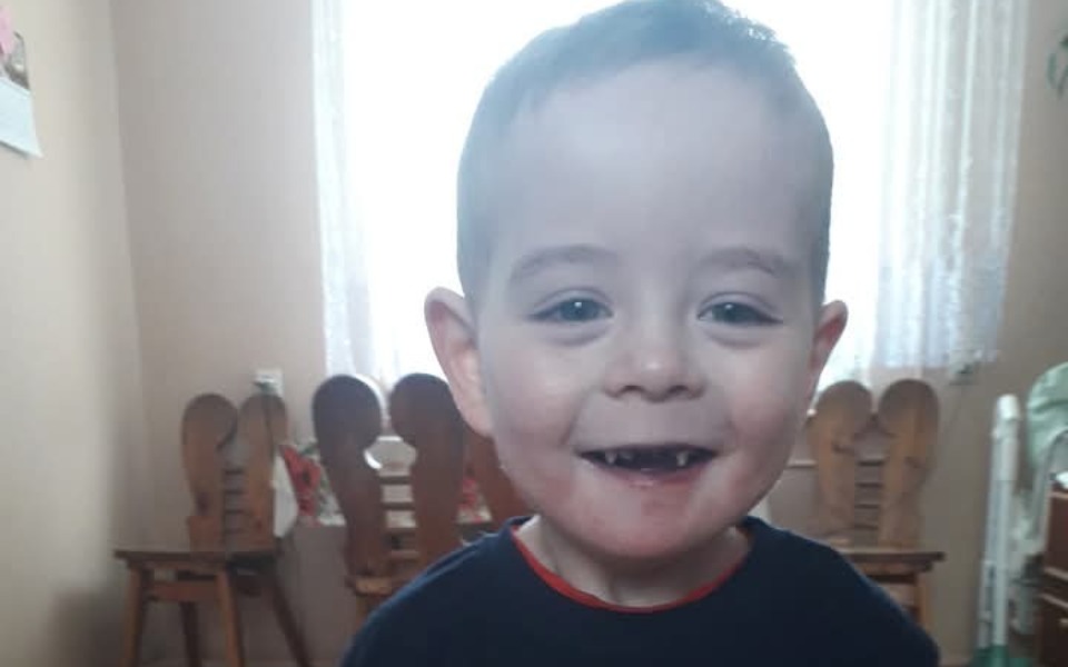 
        Uśmiechnięty chłopiec w pokoju, z zębami na wierzchu.
    