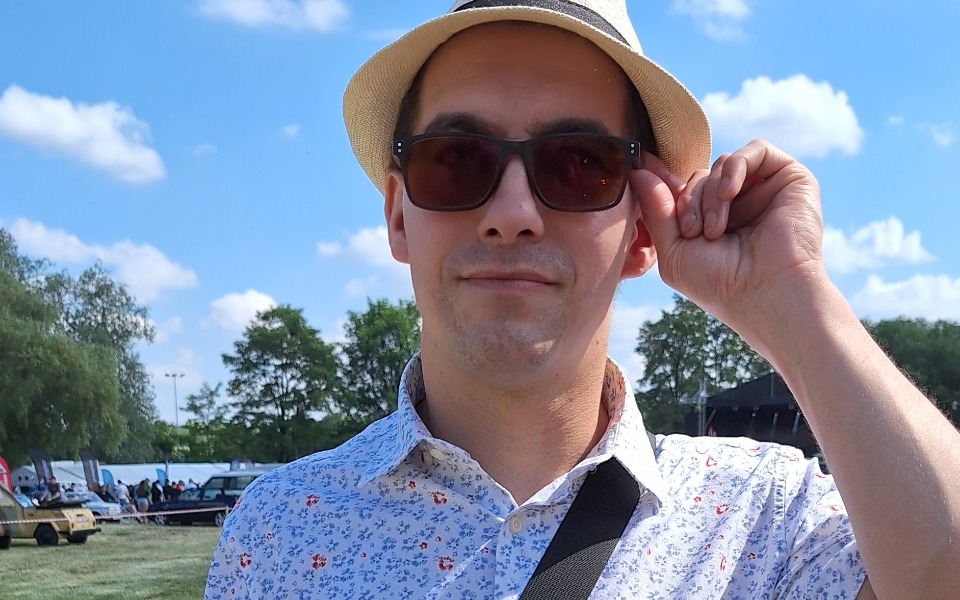 
        Mężczyzna w kapeluszu i okularach przeciwsłonecznych na tle nieba.
    