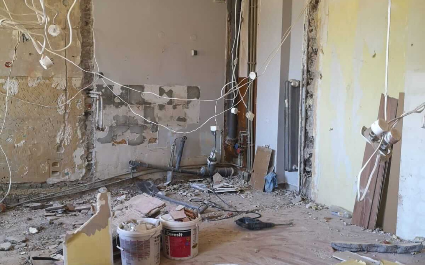 
        Zniszczone wnętrze budynku, przewody i materiały budowlane w nieładzie.
    