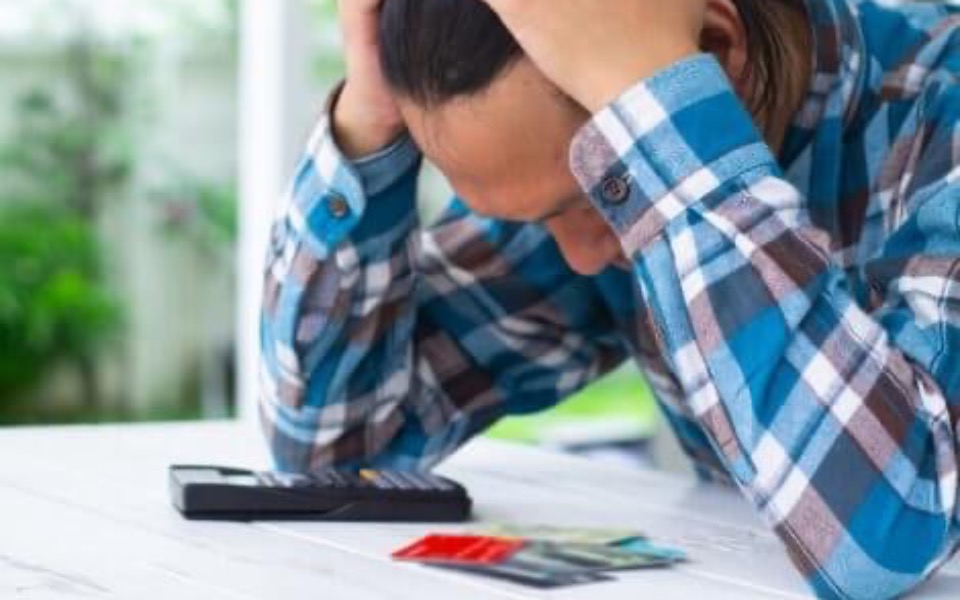 
        Zmartwiony mężczyzna z telefonem i kartami płatniczymi.
    