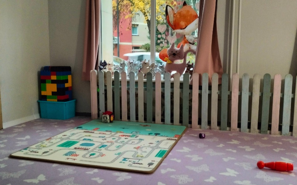 
        Pokój zabaw dla dzieci z kolorowymi klockami i dywanem z mapą.
    