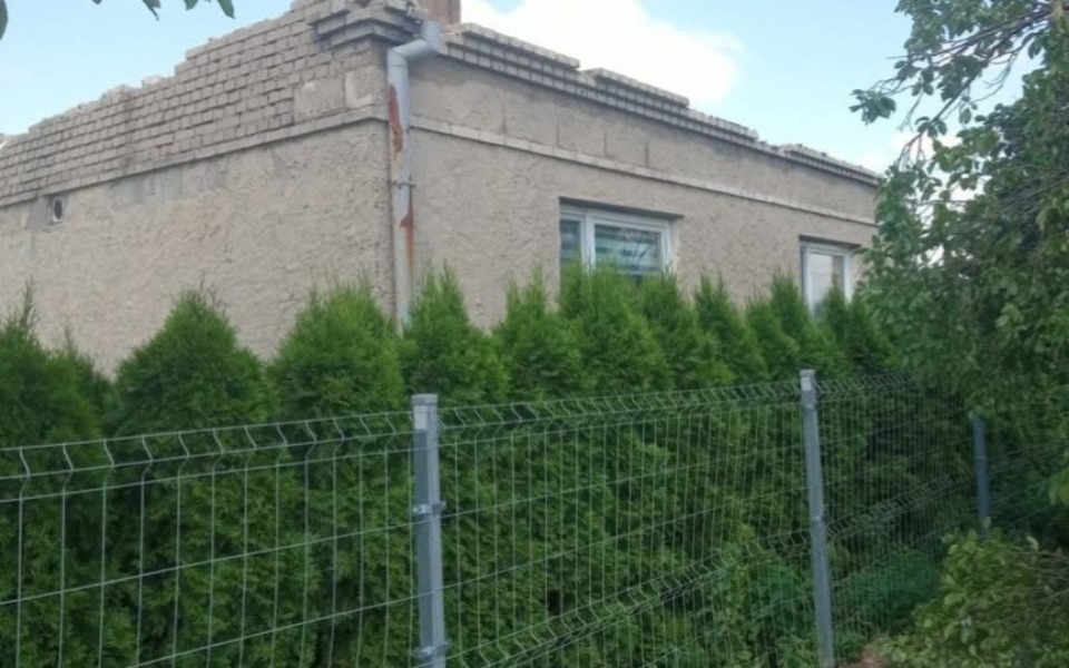 
        Widok na dom otoczony wysokimi tujami.
    
