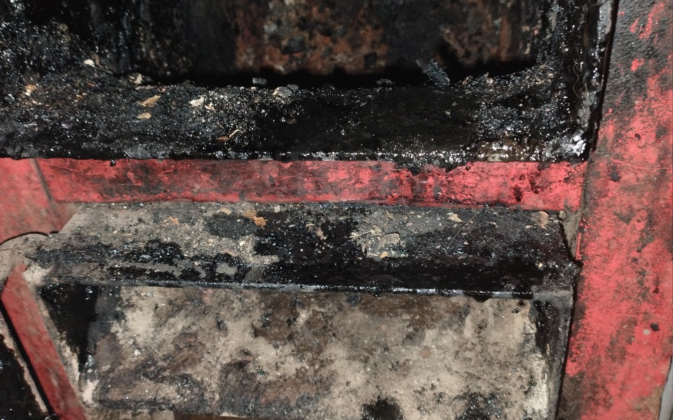 
        Zniszczona komora pieca, pokryta sadzą i zanieczyszczeniami.
    