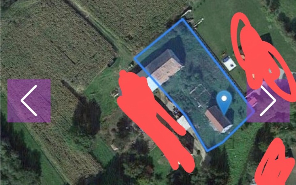 
        Widok z góry na teren z budynkami i zielenią.
    