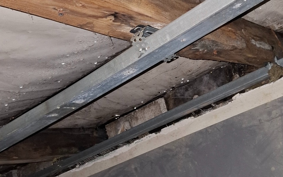 
        Widok na drewniane belki i metalowe elementy konstrukcyjne.
    