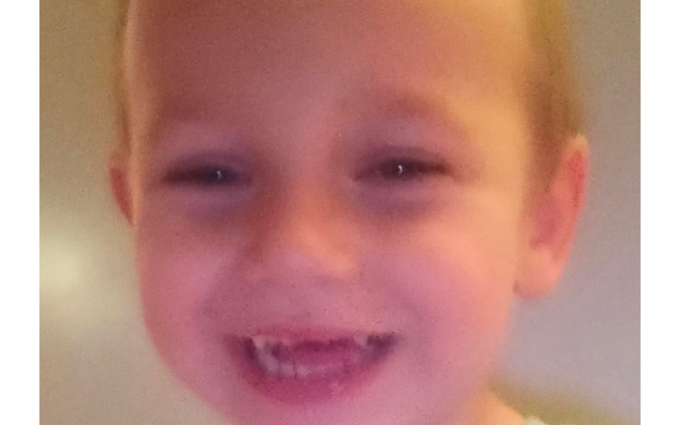 
        Uśmiechnięty chłopiec z widocznymi zębami.
    