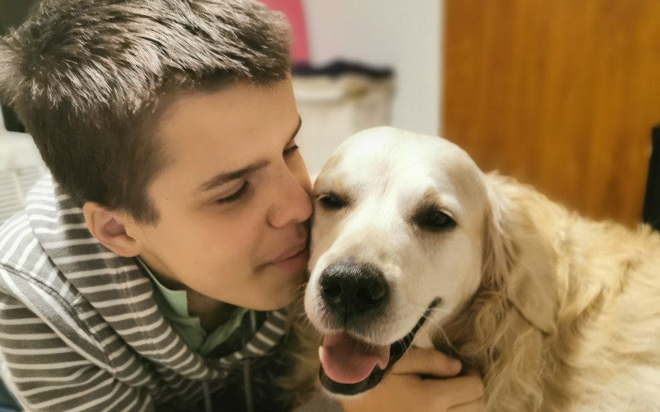 
        Chłopiec przytulający się do psa w przytulnym otoczeniu.
    