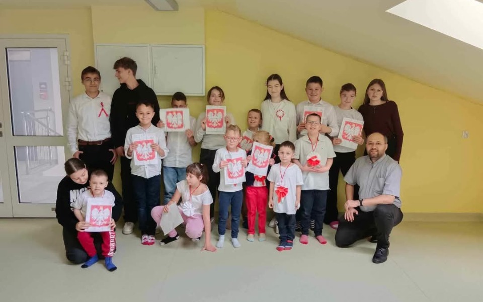 
        Grupa dzieci z rysunkami, uśmiechnięte i pełne energii.
    