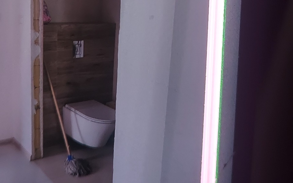 
        Widok na łazienkę z mopem i toaletą, minimalistyczny wystrój.
    