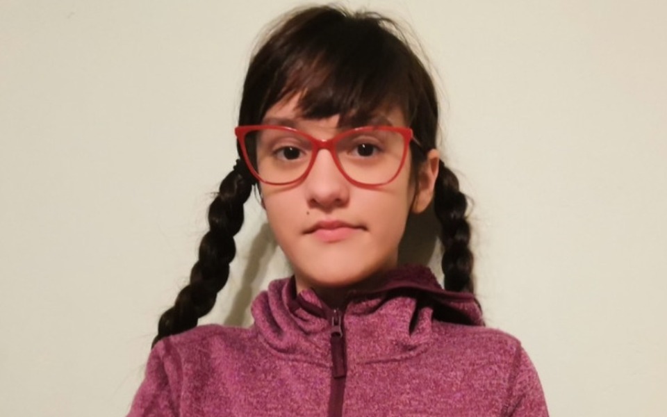 
        Młoda dziewczyna w okularach i warkoczach na tle ściany.
    