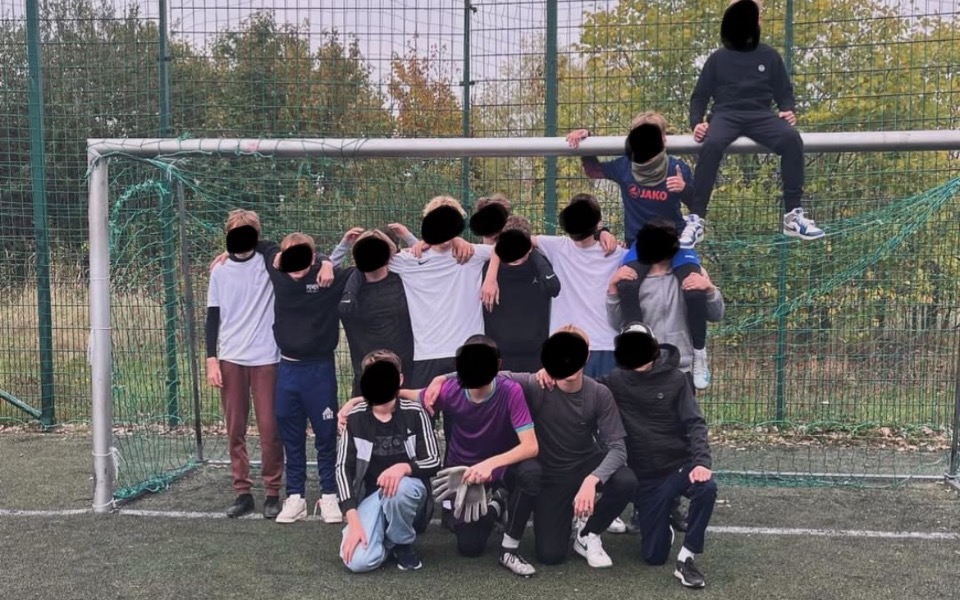 
        Grupa dzieci grających w piłkę nożną na boisku.
    