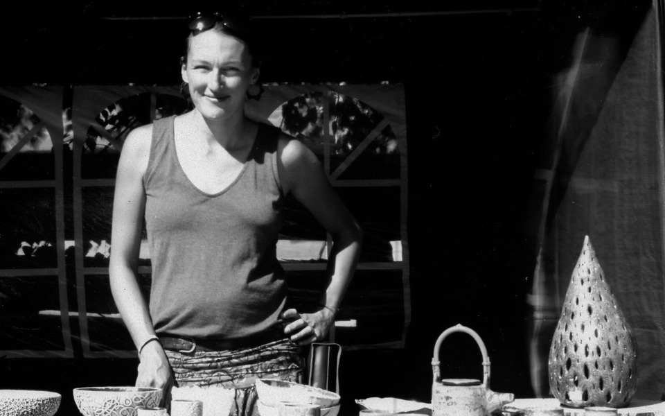 
        Kobieta przy stoisku z rękodziełem, uśmiechnięta i pełna energii.
    