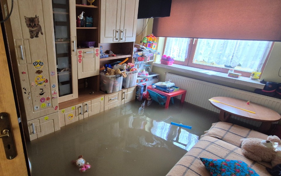 
        Zalane wodą pomieszczenie z zabawkami i meblami.
    