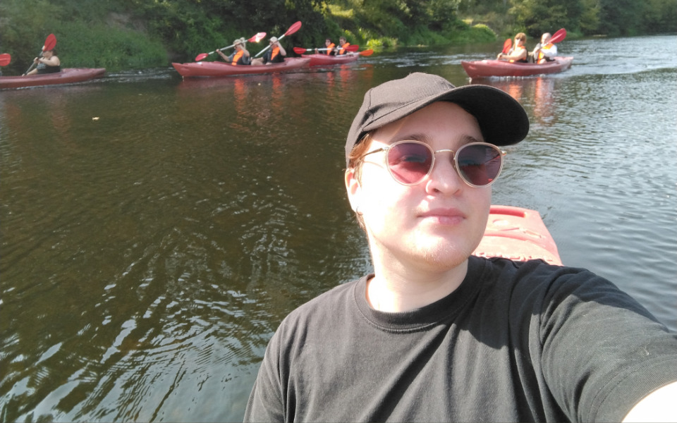 Osoba na kajaku, w tle grupa pływających kajaków.