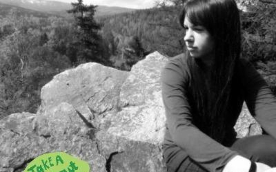 
        Młoda dziewczyna na tle górskiego krajobrazu.
    