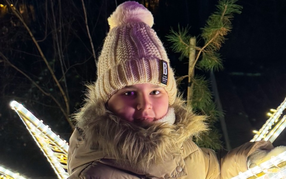 
        Chłopiec w ciepłej czapce i kurtce, uśmiechający się w zimowej scenerii.
    