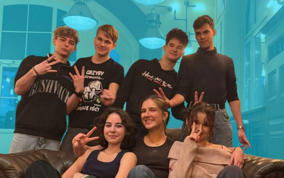 
        Grupa młodych ludzi pozujących na kanapie, w radosnej atmosferze.
    