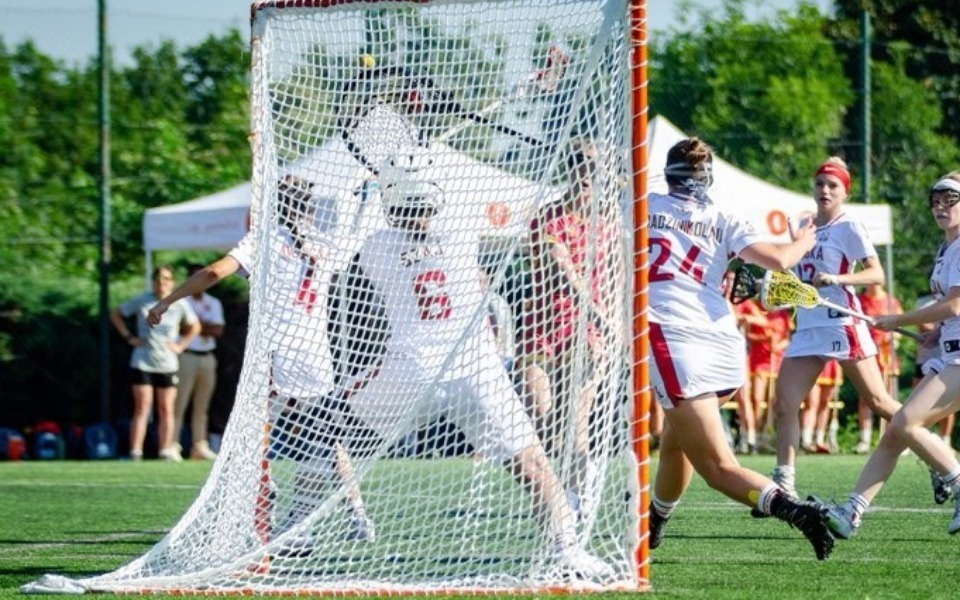 
        Mecz lacrosse, zawodnicy w akcji na boisku.
    