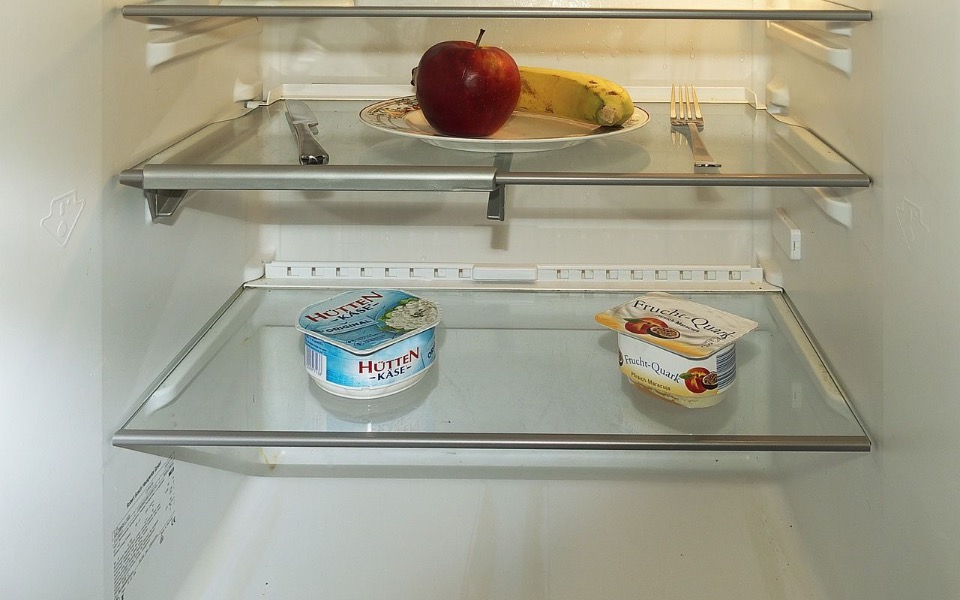 
        Pusty lodówka z jabłkiem i bananem na półce.
    