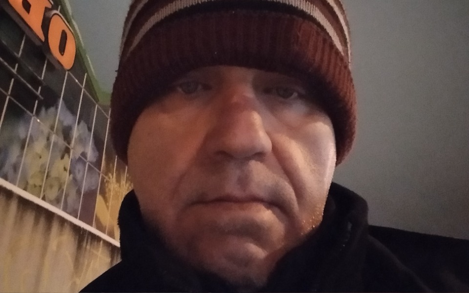 
        Mężczyzna w czapce, patrzący w kamerę.
    