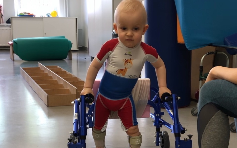 
        Małe dziecko korzystające z chodzika w rehabilitacji.
    