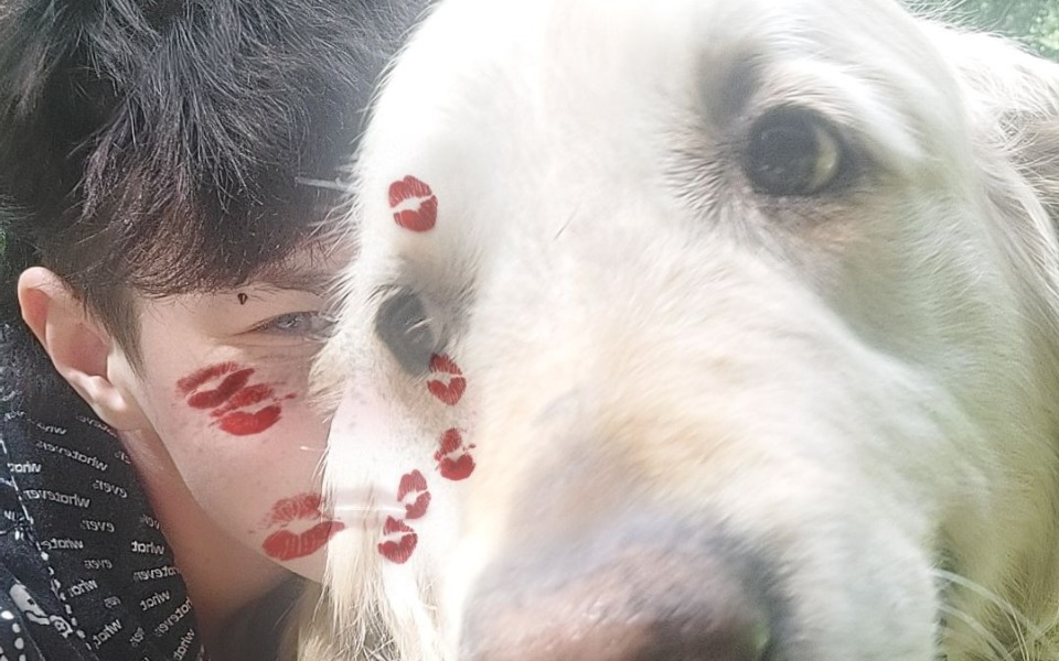 
        Chłopak z psem, na jego twarzy ślady pocałunków.
    