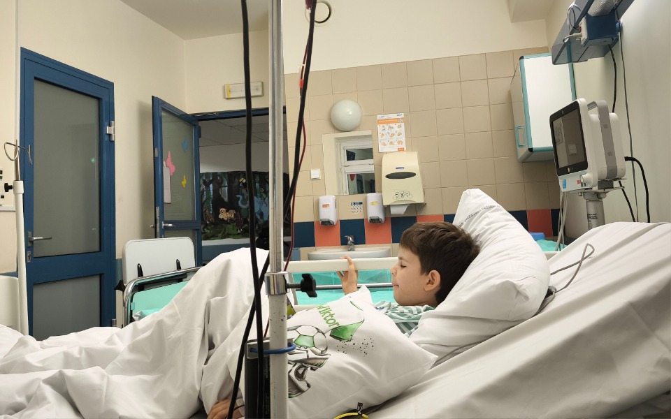 
        Chłopiec leży w szpitalnym łóżku, korzystając z telefonu.
    