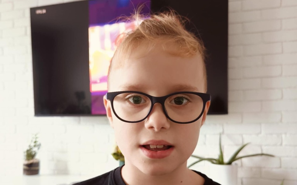 
        Chłopiec w okularach, patrzy w kamerę.
    