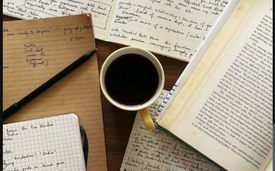 
        Kawa i notatki na biurku, z książką w tle.
    