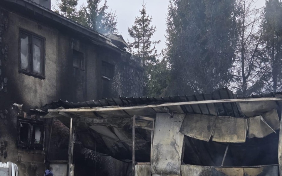 
        Zniszczony budynek po pożarze, z dymem i zniszczeniami.
    