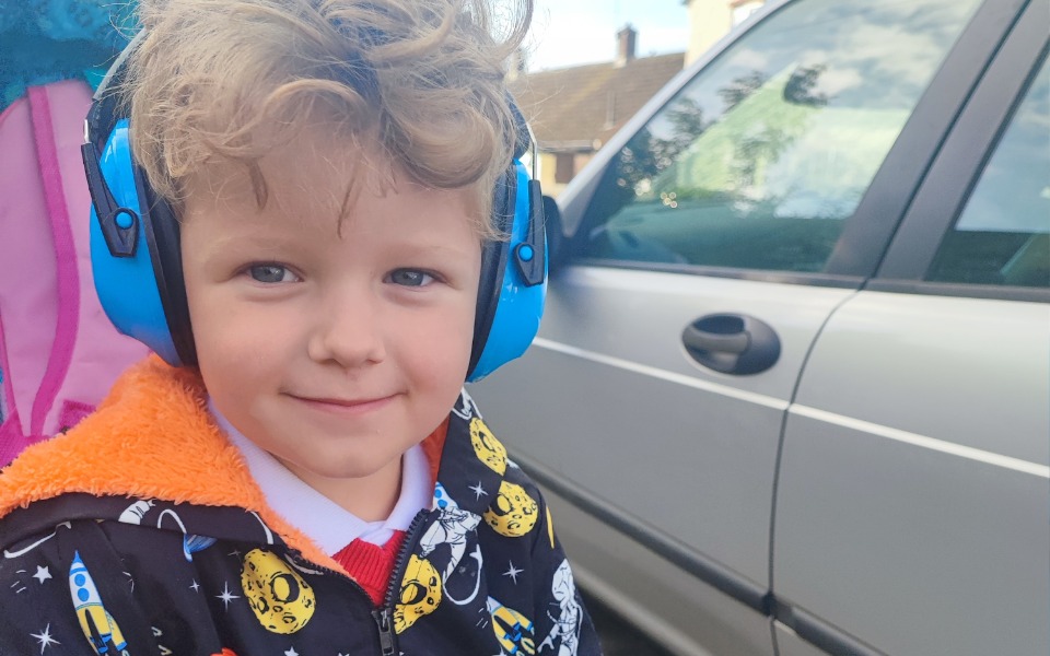 
        Chłopiec w słuchawkach, uśmiechający się do kamery.
    