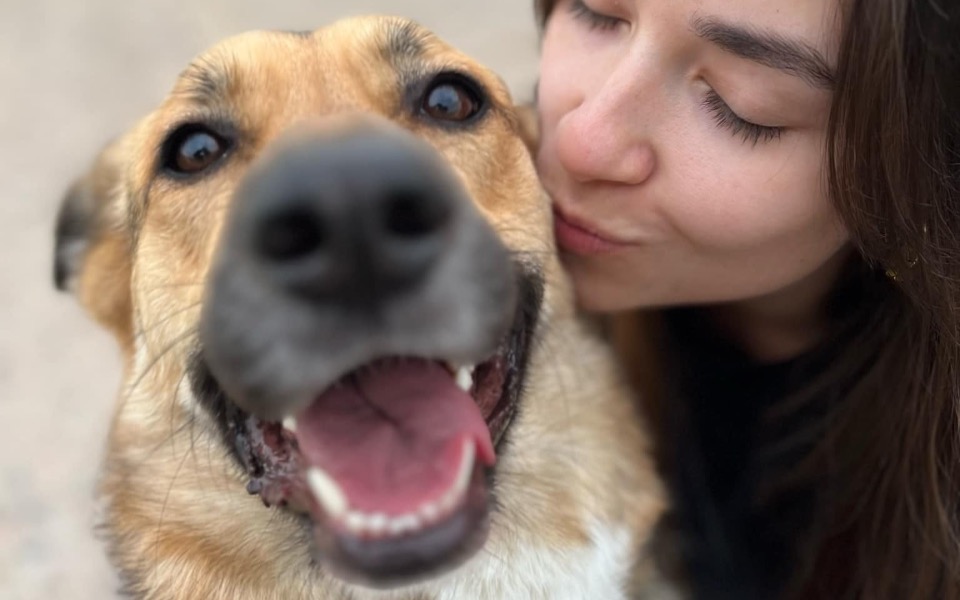 
        Kobieta całuje psa, oboje uśmiechnięci.
    